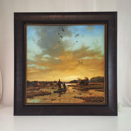 An original oil of two duck hunters wading a marsh under a gold sunset sky, in a dark burl frame